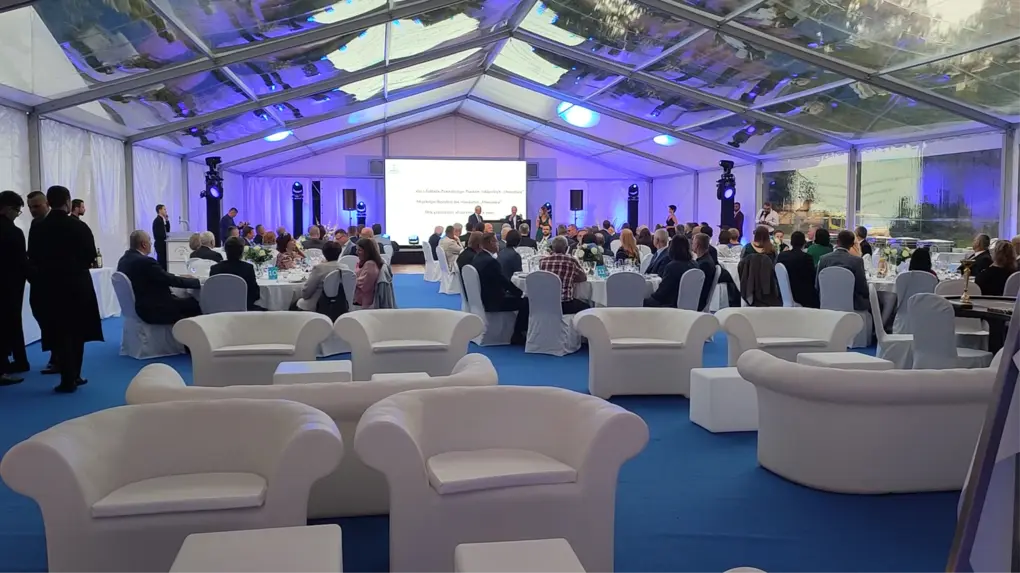 Wnętrze namiotu eventowego podzielone na strefy: scena, stoły i część loungowa